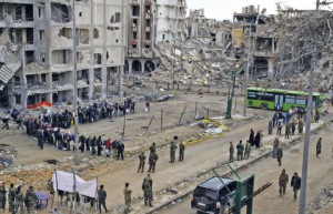 Forces loyal to Syria's President Bashar al-Assad supervise the evacuation process of rebel fighters from the Old City of Homs